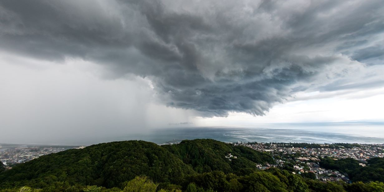 Thunderstorms above a verdant hill. 