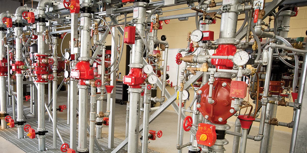 industrial fire protection system with sprinkler piping, control valves, and pressure gauges used for fire safety training and system maintenance