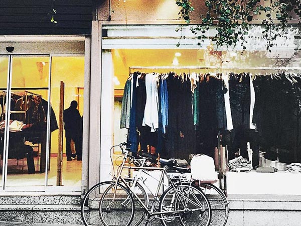 Fashion storefront with clothing display and a parked bicycle outside.