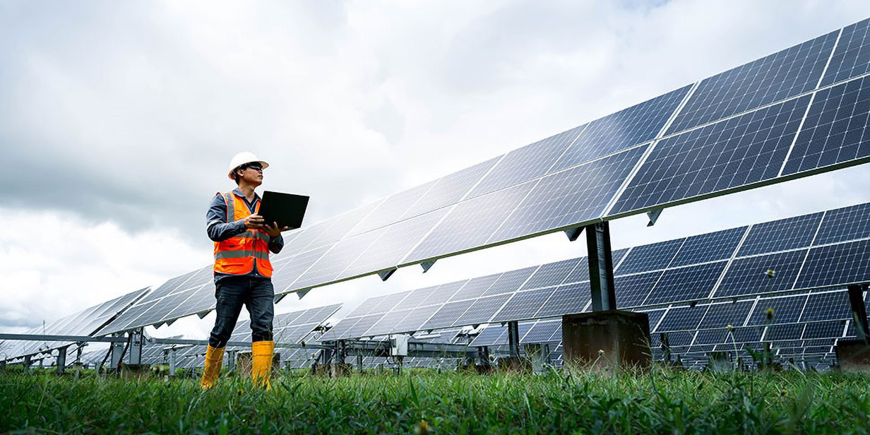 A worker walks through a field of solar panels.