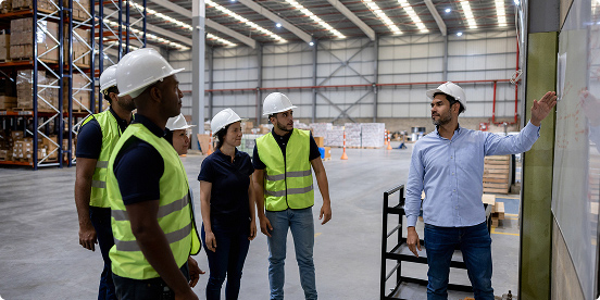 workers gathering looking at a whiteboard of tasks
