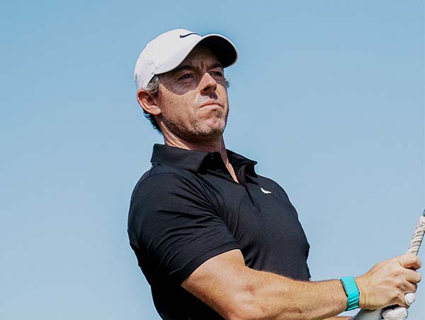 Rory-McIlroy end of swing, strategic approach in golf, outdoor sports activity, golf as a wellness activity, FM mission of promoting health, golf attire and equipment, coastal golf course scene, enhancing concentration through sports, strategic thinking in golfing, benefits of golfing for mental health