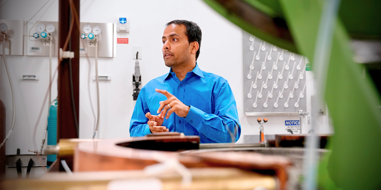 engineer in blue shirt in industrial laboratory with control panels, gauges, and machinery equipment